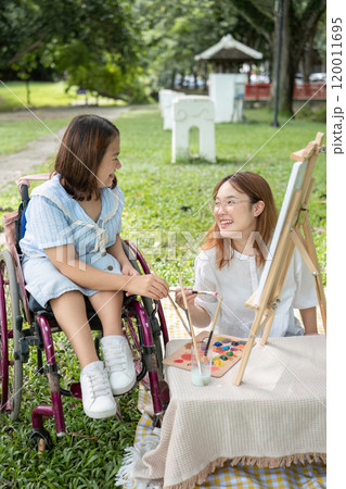 Close Friends, Disabled Young Women Drawing Together Outdoors in a Park, Sharing Creativity and Friendship 120011695