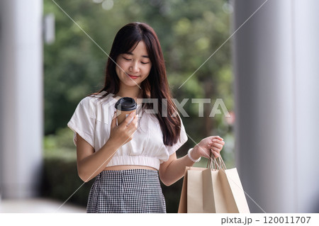 Young Woman Shopping with Paper Bag at Department Store, Enjoying a Day Out in Casual Fashion Young Woman Shopping with Paper Bag at Department Store, Enjoying a Day Out in Casual Fashion 120011707