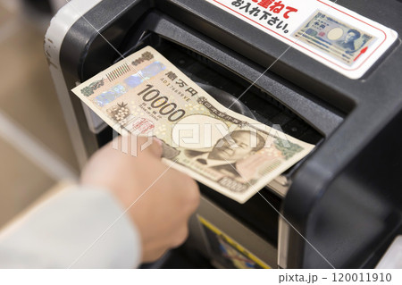 自動精算機に新札を入れる女性手元 120011910