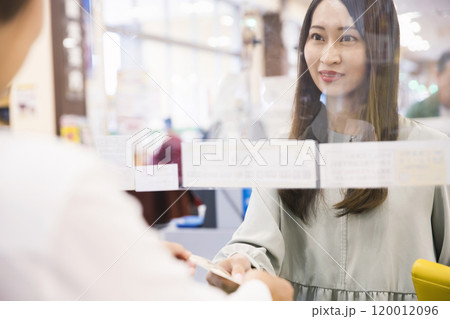 スーパーのレジで現金を手渡しする女性 スーパーのレジで現金を手渡しする女性 120012096