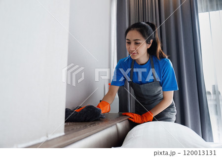Cleaning service woman cleans dust on the headboard with a cloth. House cleaning service concept Cleaning service woman cleans dust on the headboard with a cloth. House cleaning service concept 120013131