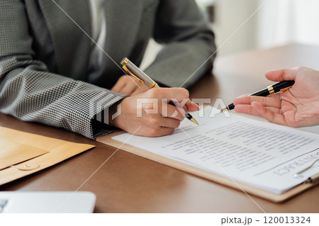 A woman is signing a document with a pen 120013324