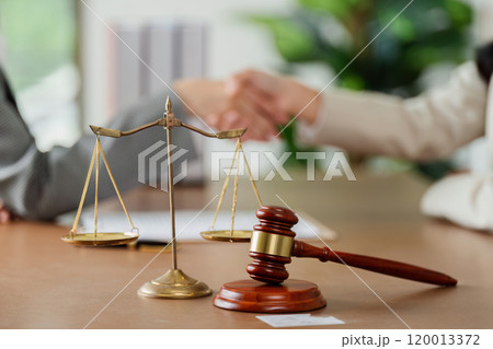 law and justice is represented by a mallet gavel of the judge, scales of justice, lawyer and client shaking hands 120013372