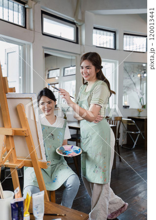 beautiful young woman artist working on painting something on a large canvas 120013441