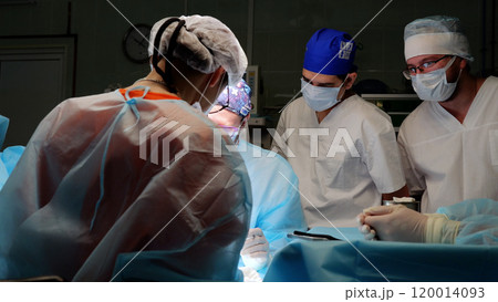 Skilled surgeons in a bright operating room perform a life saving procedure, focused and collaborating in a sterile environment with medical equipment 120014093