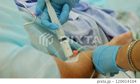 Surgeon administering medication through iv during surgical procedure in hospital operating room, with healthcare team collaborating for optimal patient care Surgeon administering medication through iv during surgical procedure in hospital operating room, with healthcare team collaborating for optimal patient care 120014104