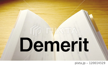 スポットライトの当たったテーブルで開いた本にDemeritの文字_ワイド 120014329