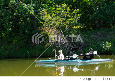 Family kayak trip for seigneur and senora. An elderly married couple rowing a boat on the river, a water hike, a summer adventure. Age-related sports, mental youth and health, tourism, active old age 120014341