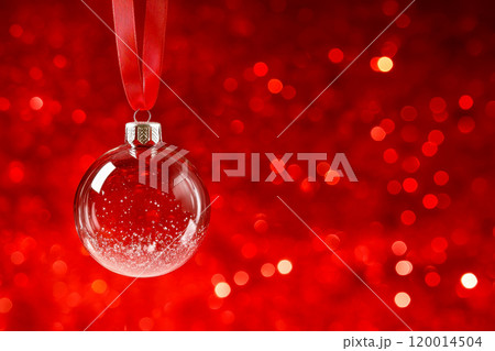 Transparent empty Christmas bauble. Transparent empty Christmas ball hanging on red ribbon on isolated red background. 120014504