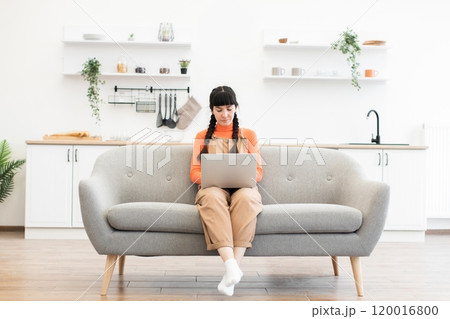Young woman working on laptop in modern minimalist living room 120016800