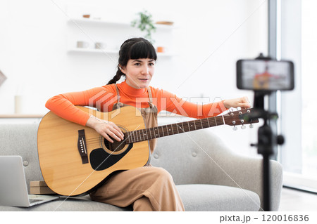 Caucasian female blogger recording guitar lesson at home studio setting Caucasian female blogger recording guitar lesson at home studio setting 120016836