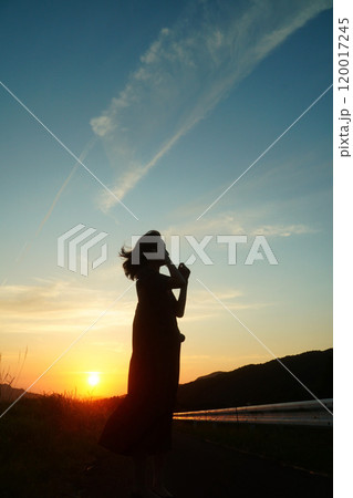 夕陽の空を見上げる女性 120017245