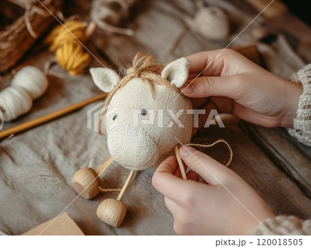 Close-up of hands sewing a handmade fabric toy in a craft workshop. 120018505