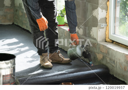 Repair work inside the house, waterproofing the floor, a man with a kerosene lamp. Repair work inside the house, waterproofing the floor, a man with a kerosene lamp. 120019937