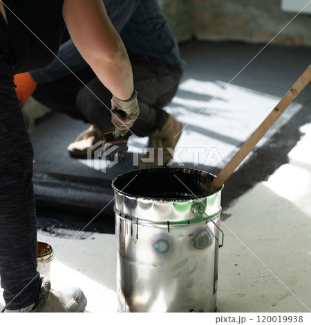 A man and a woman are engaged in waterproofing the floor in the house. A man and a woman are engaged in waterproofing the floor in the house. 120019938