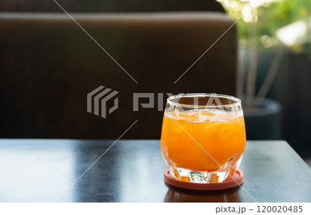 Refreshing glass of fresh orange juice with ice on brown wooden table. Refreshing glass of fresh orange juice with ice on brown wooden table. 120020485