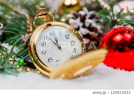 A vintage clock in the snow against the background of a Christmas tree and a garland 120021631