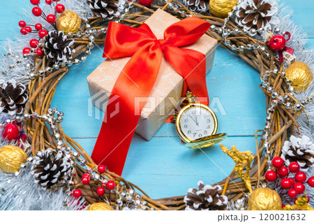 A vintage clock in the snow against a background of a gift and a Christmas wreath 120021632
