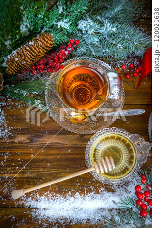 Christmas background, cup of tea with honey and croissant, branch of a Christmas tree in the snow 120021638