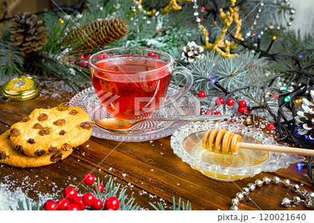 Christmas tea in glass Cup . composition with cookie, pine branches, cones on background of garlands on wooden table Christmas tea in glass Cup . composition with cookie, pine branches, cones on background of garlands on wooden table 120021640