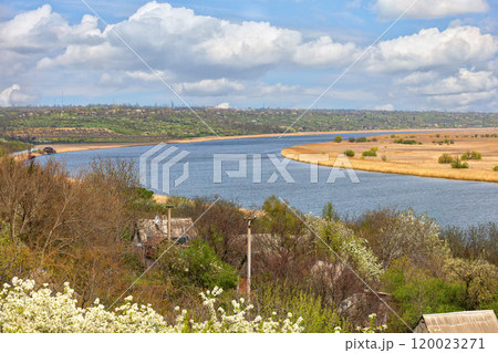 A tranquil river view winding through lush landscapes under a bright blue sky in springtime 120023271