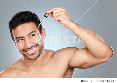 Skincare, smile or man with serum in studio for treatment, avocado oil or anti aging product. Male person, pipette or thinking for skin routine with vitamin c, liquid or cosmetics on gray background 120024512