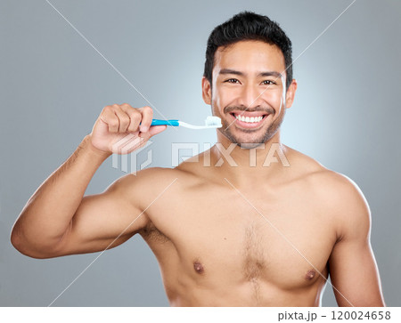 Brushing teeth, portrait and smile of shirtless man in studio on gray background for cosmetic wellness. Dental hygiene, oral care and toothbrush with happy person in bathroom for cleaning routine 120024658