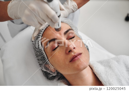 Woman receiving a skincare treatment at a spa in a serene environment 120025045