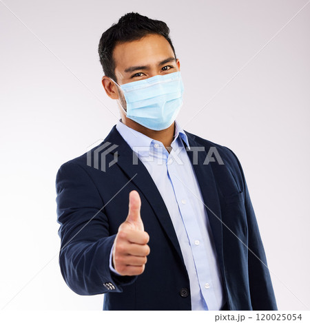 Man, portrait and thumbs up in studio with mask on white background for health, safety and compliance. Business person, happiness and positive hand gesture for covid, healthcare and thank you sign 120025054