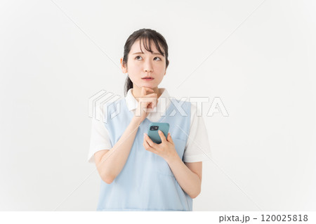エプロンの女性 保育士 介護士 スマホ 悩む エプロンの女性 保育士 介護士 スマホ 悩む 120025818