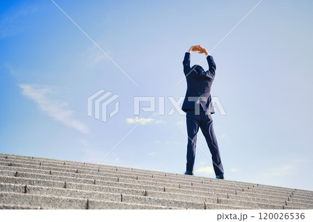 ビジネスイメージ　スーツ姿で伸びをする若い男性　 120026536