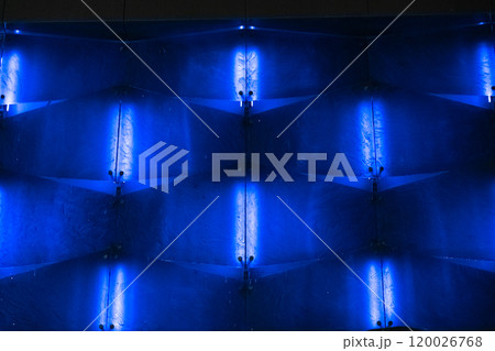 The illuminated, blue, glass facade of the building at night. Glazed background The illuminated, blue, glass facade of the building at night. Glazed background 120026768