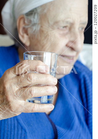 closeup wrinkled hand of old senior woman holding water glass. closeup wrinkled hand of old senior woman holding water glass. 120027209