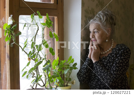 Old beautiful woman at the window. A very old woman. An eighty-year-old woman. Studio portrait of an old woman. Lonely old age. Nursing home 120027221