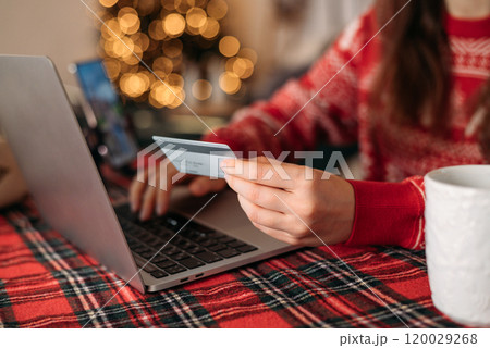 Christmas sales and online shopping. Hand with credit card on laptop at table on Christmas decorations Christmas sales and online shopping. Hand with credit card on laptop at table on Christmas decorations 120029268