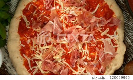 Super slow motion of falling fresh basil leaves on pizza dough with sugo, top down view 120029996
