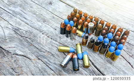 Various types of bullets displayed on a wooden surface, symbolizing the theme of firearm safety, the impact of violence, and the importance of responsible use and control of firearms. 120030335