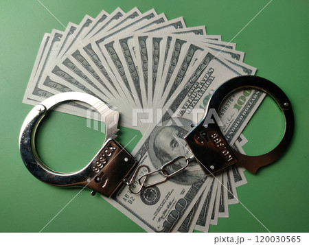 Top view banknotes and metal hand cuff on a green background. Top view banknotes and metal hand cuff on a green background. 120030565