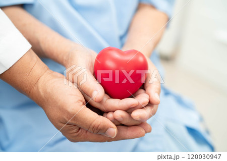Asian elder senior woman patient holding red heart in hospital. 120030947