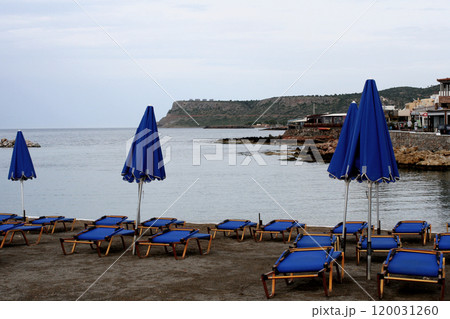 Crete, Greece, an empty beach with blue sunshade and beds, sea view without waves 120031260