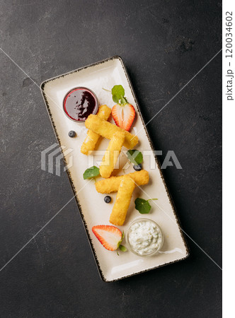 Crispy cheese sticks served with berry sauce and herb dip on a stylish plate, garnished with fruits Crispy cheese sticks served with berry sauce and herb dip on a stylish plate, garnished with fruits 120034602