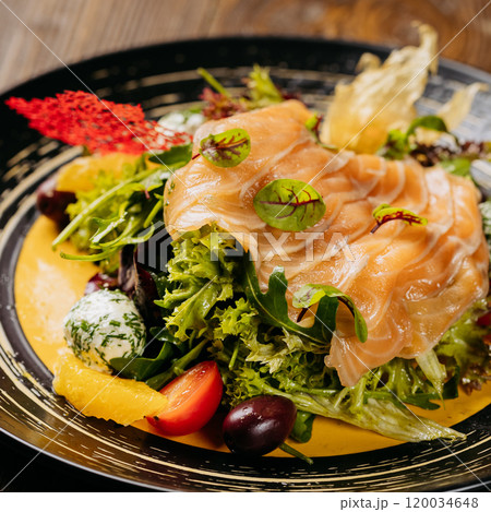 Top view of a gourmet salad with smoked salmon, vibrant greens, and artistic garnishes on table 120034648
