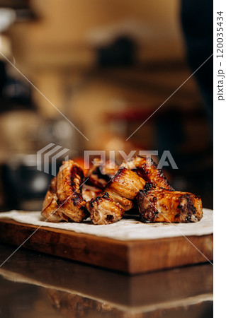 Close-up of grilled meat ribs served on a wooden board, perfect for a hearty and flavorful meal 120035434