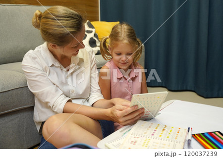 A mother supports her daughter with homework A mother supports her daughter with homework 120037239