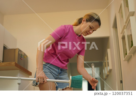 A woman is cleaning her living room at home 120037351