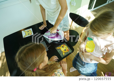 Teacher in workshop teched two girls how to assemble a thermo mosaic  120037555