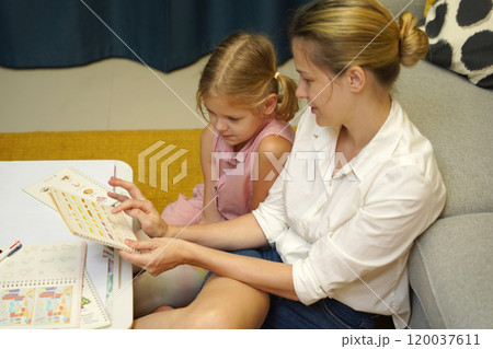 A mother supports her daughter with homework 120037611