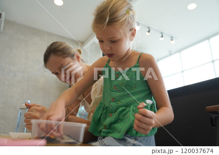 Mother and her daughter paint Halloween cookies  120037674