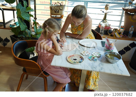 A young mother and her daughter enjoy a creative art session at home A young mother and her daughter enjoy a creative art session at home 120037682
