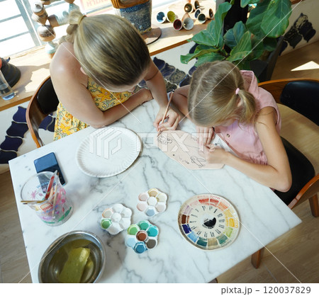 A young mother and her daughter enjoy a creative art session at home  120037829